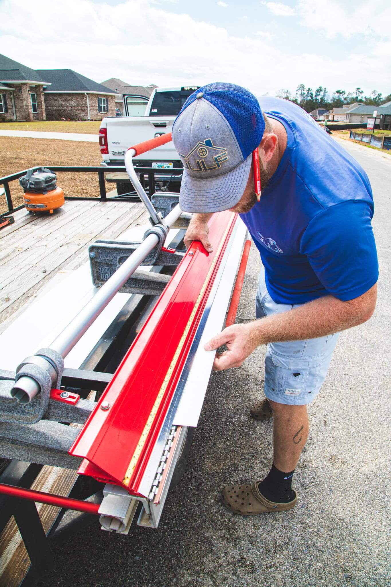 guy prepairing a red colored gutter for intsalling for a house